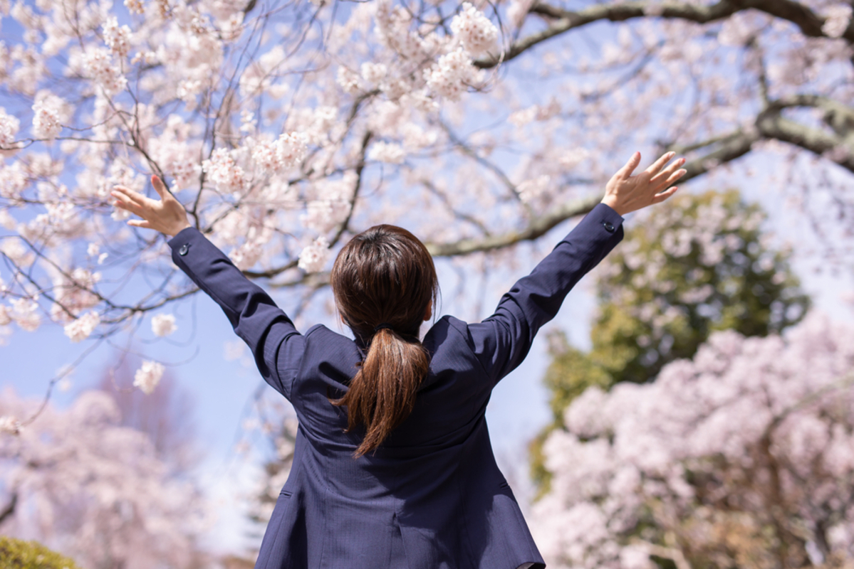 桜の前で手を広げる女性