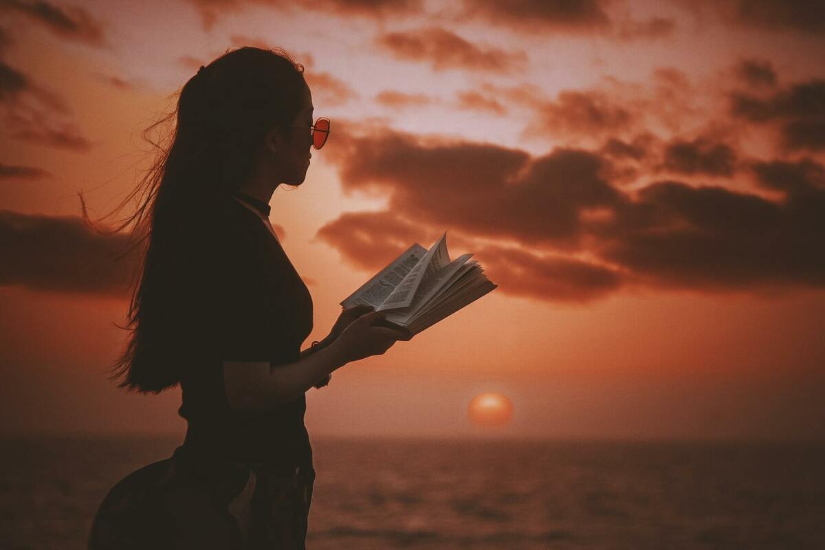 夕陽と本を読む女性