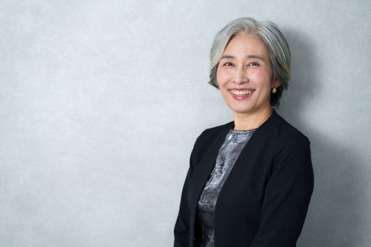 落ち着いた服装で同窓会に参加する60代女性