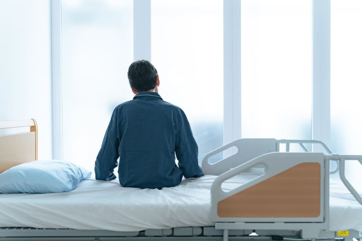 病院のベッドに座る男性