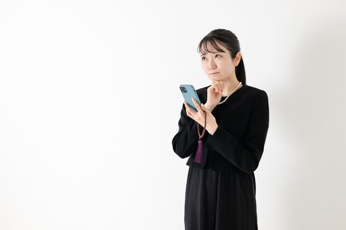 メールで送る葬儀後のねぎらいの言葉をスマホで打つようす