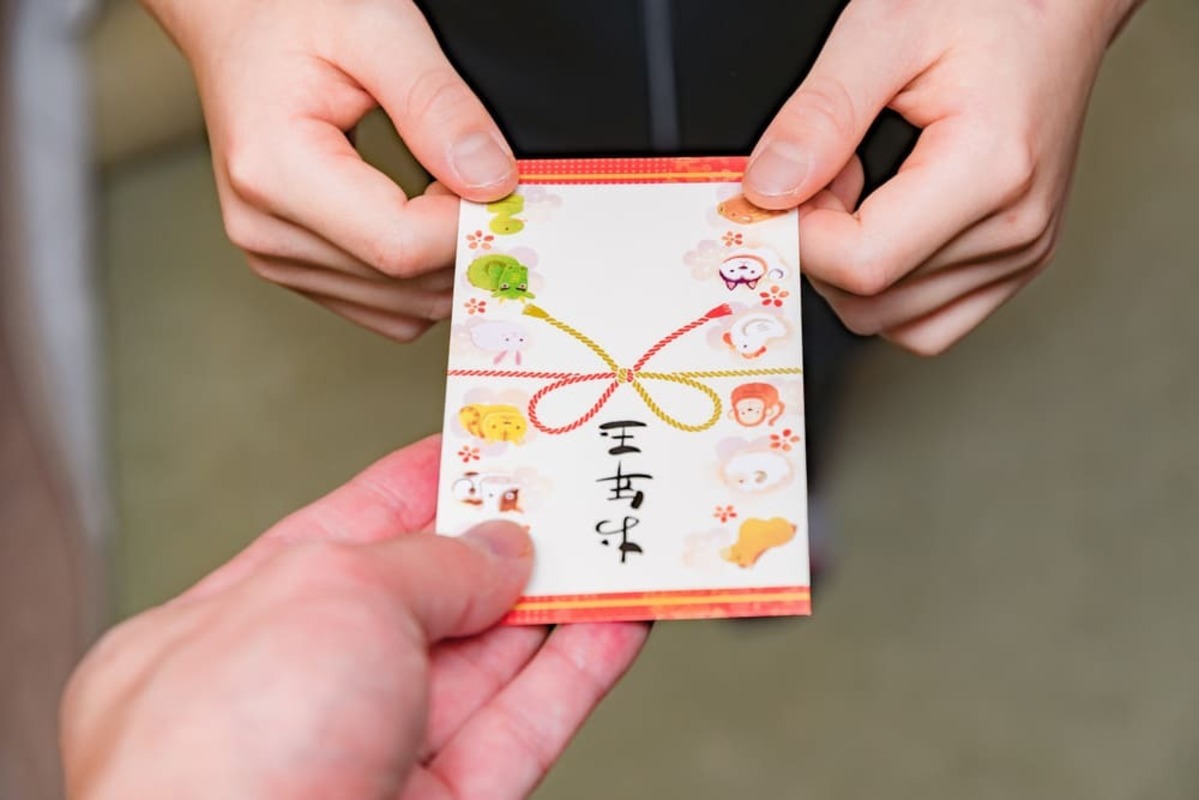 孫へのお年玉の相場 ポチ袋を渡す手元アップ