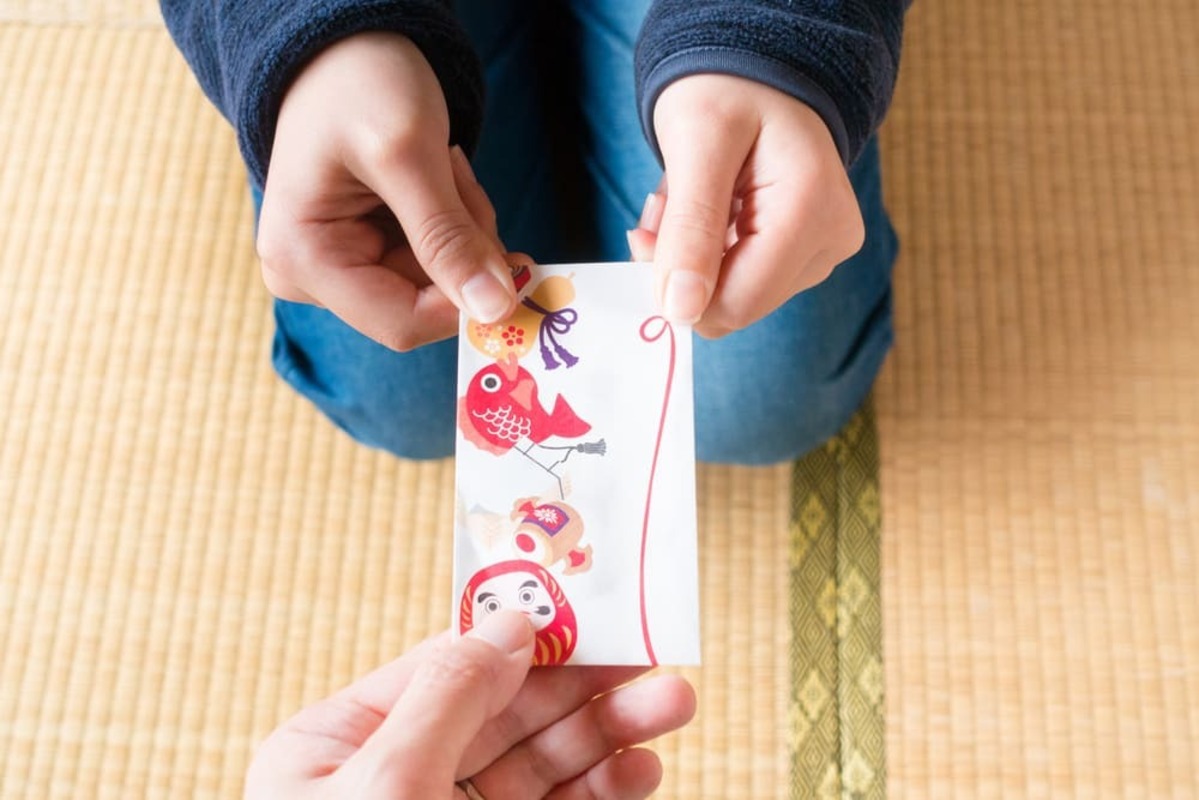 孫へのお年玉の相場 和室でポチ袋を渡す手元