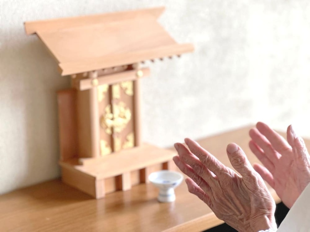 神棚 喪中　神棚に拍手する高齢女性