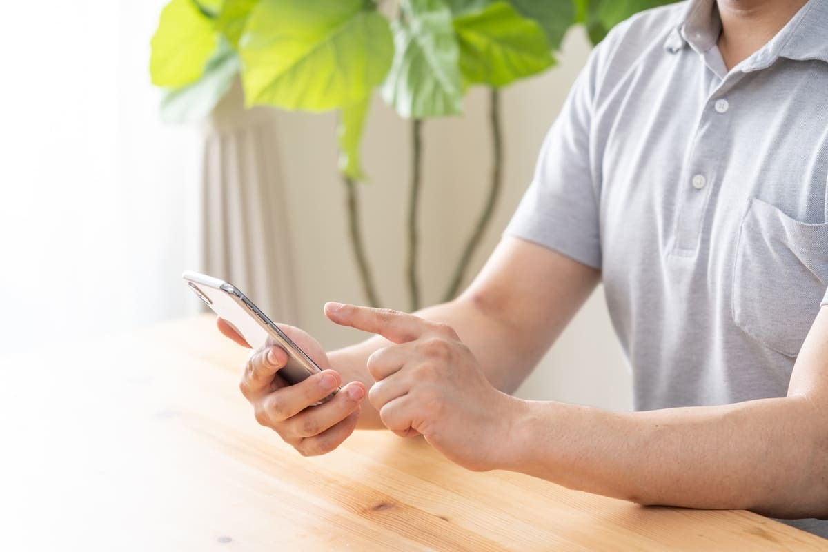 お悔やみメールへの返信 スマホでメールを返信する男性