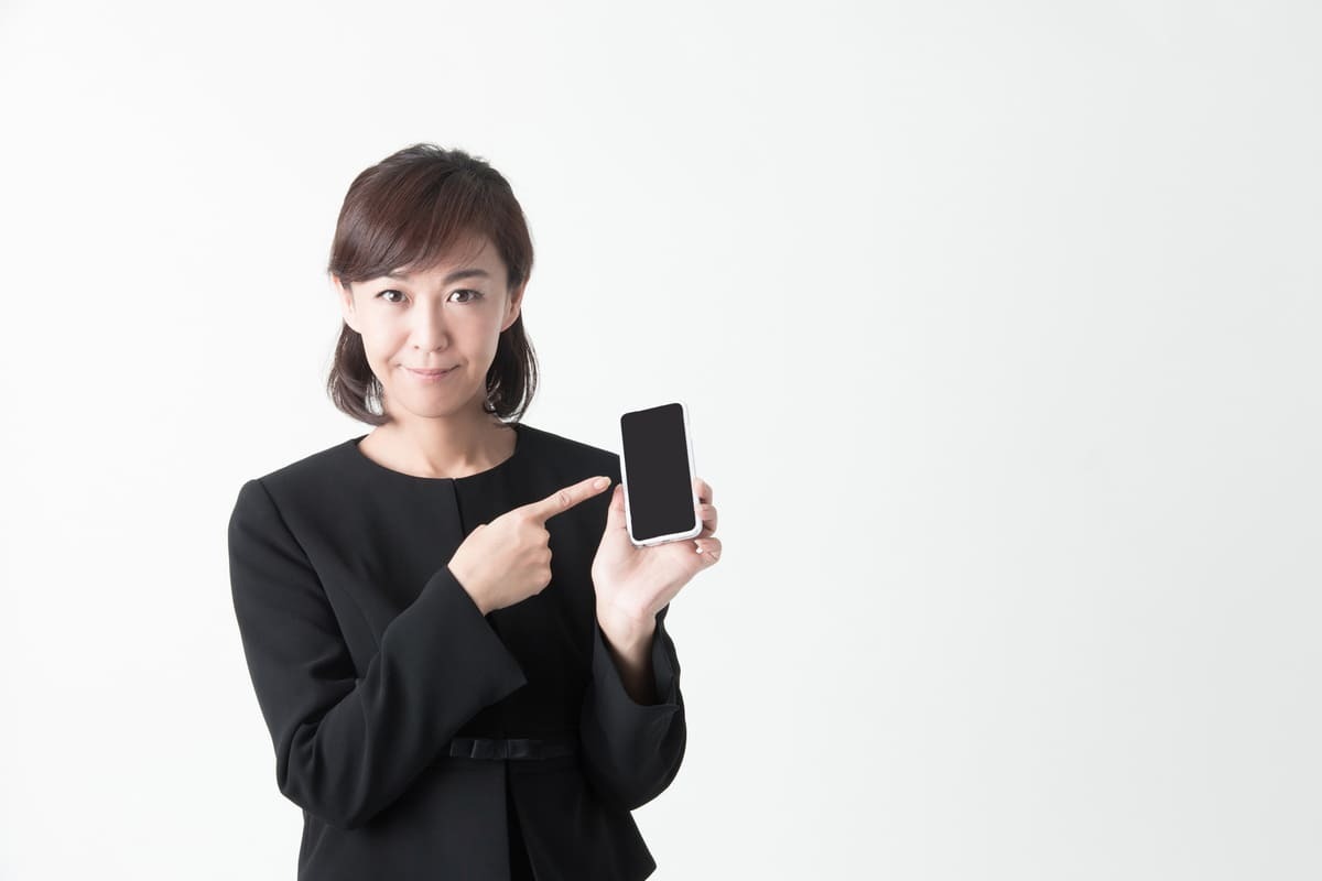 お悔やみメールへの返信 スマホを指差す女性