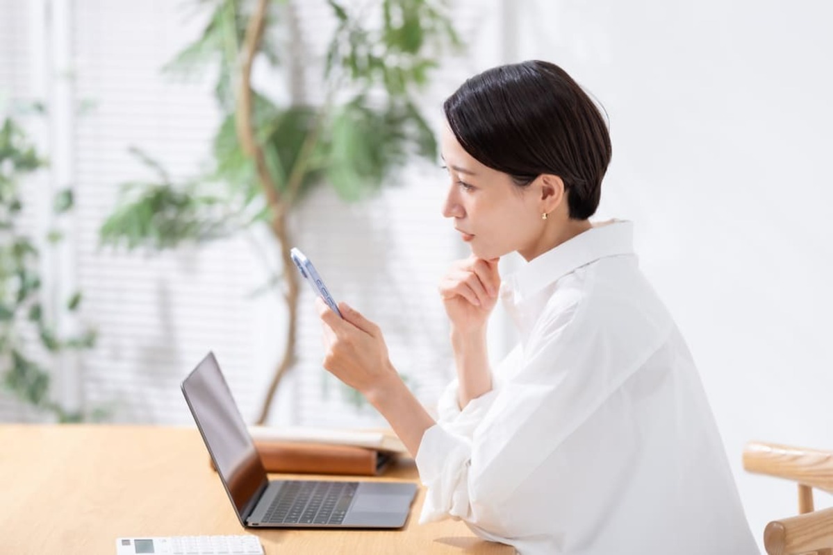 スマホを見て悩む女性