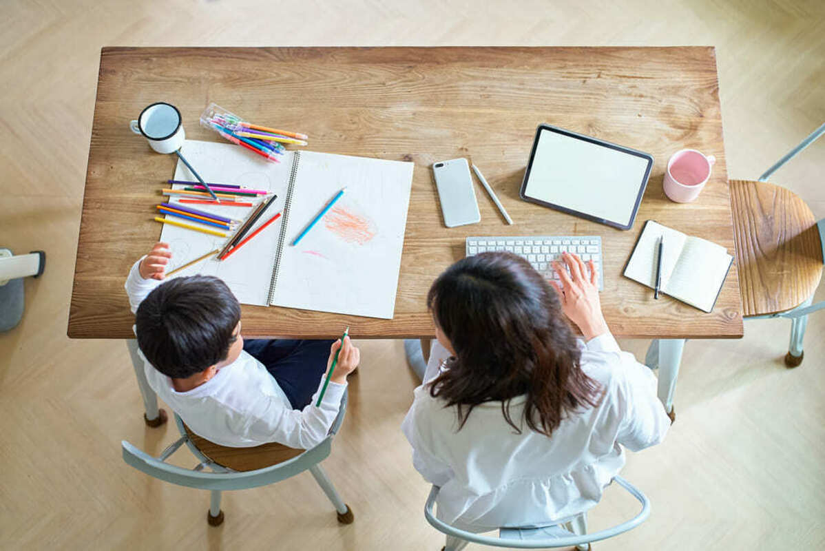 子供の宿題を見ながら仕事をする女性