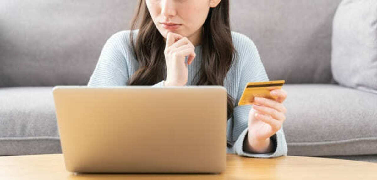 クレジットカードを持って悩む女性