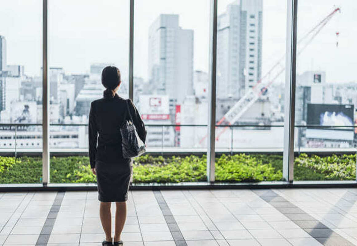外を眺めるスーツの女性
