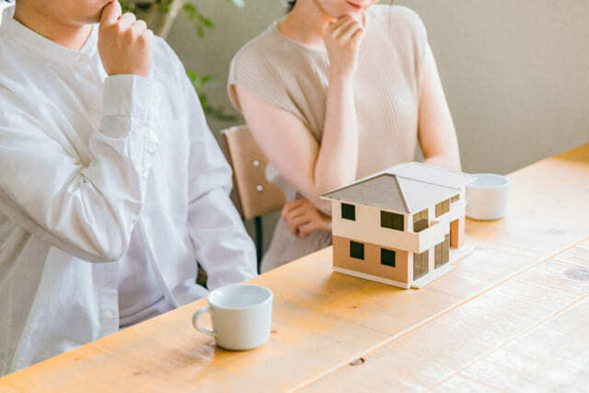 家のミニチュアを前に考える夫婦