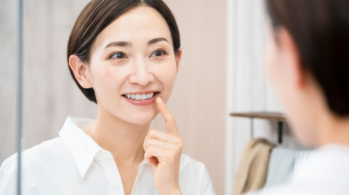 見出し画像 鏡で歯をチェックする笑顔の女性